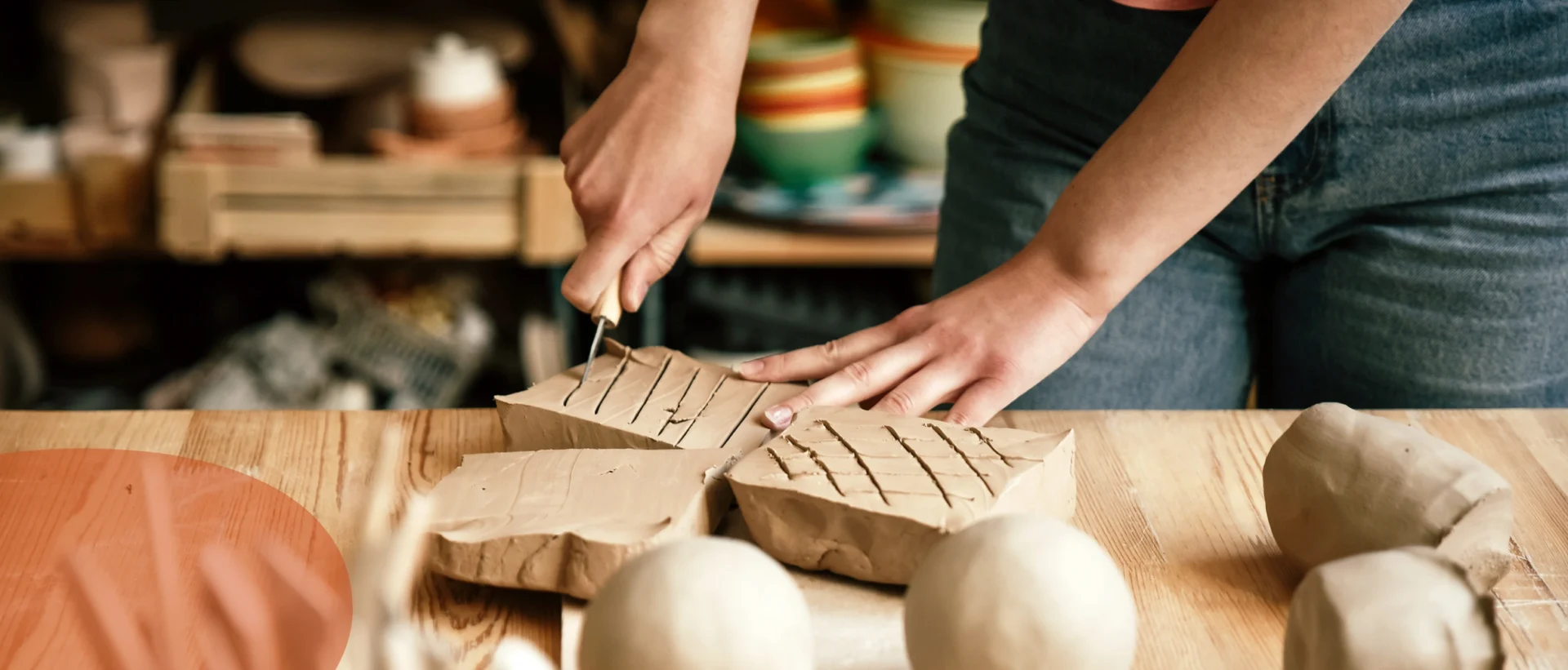 Person slicing pottery clay into rectangular pieces on a wooden surface in a pottery studio.